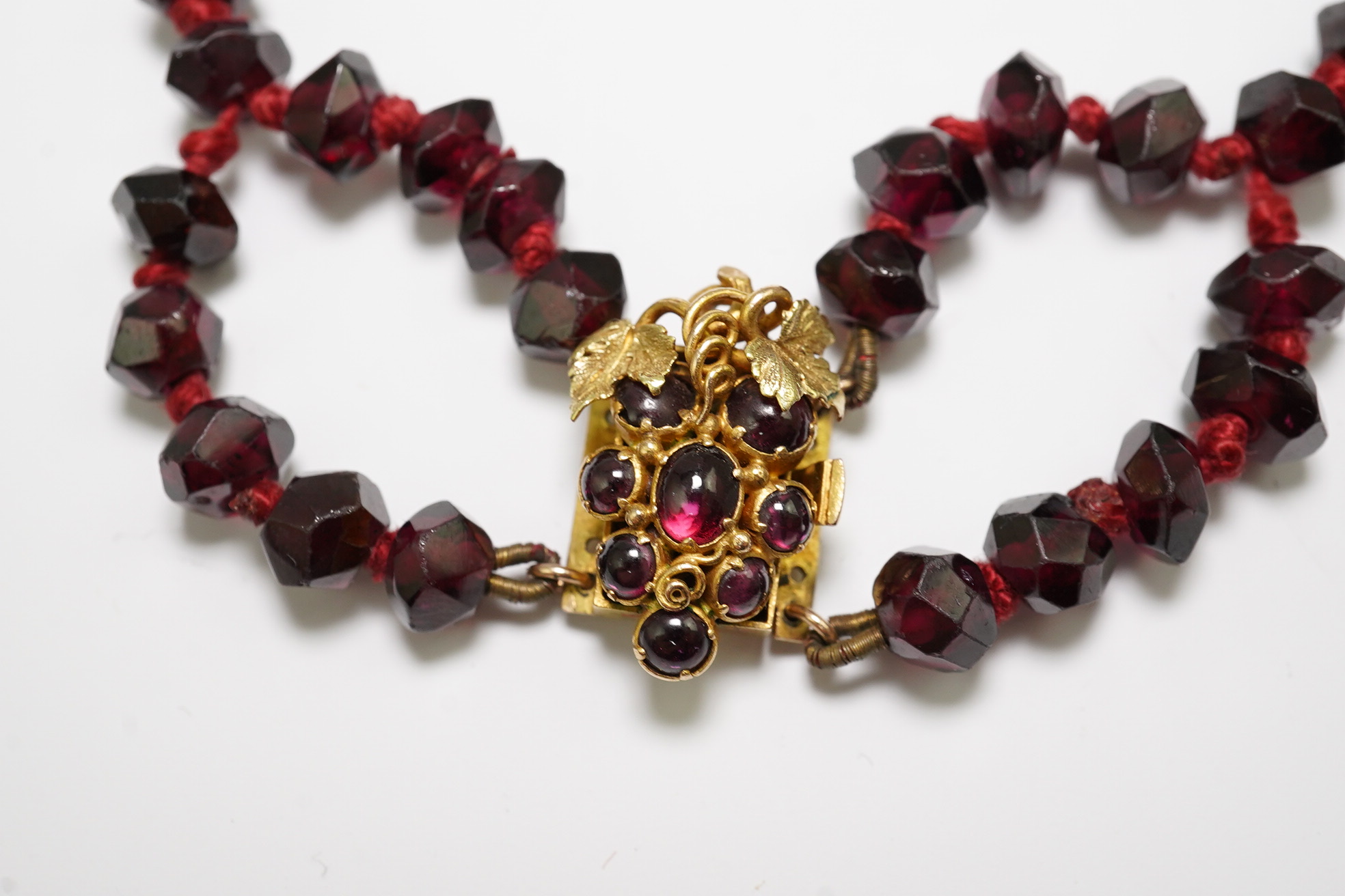 A Victorian facet cut garnet necklace, with cabochon garnet cluster set gold clasp